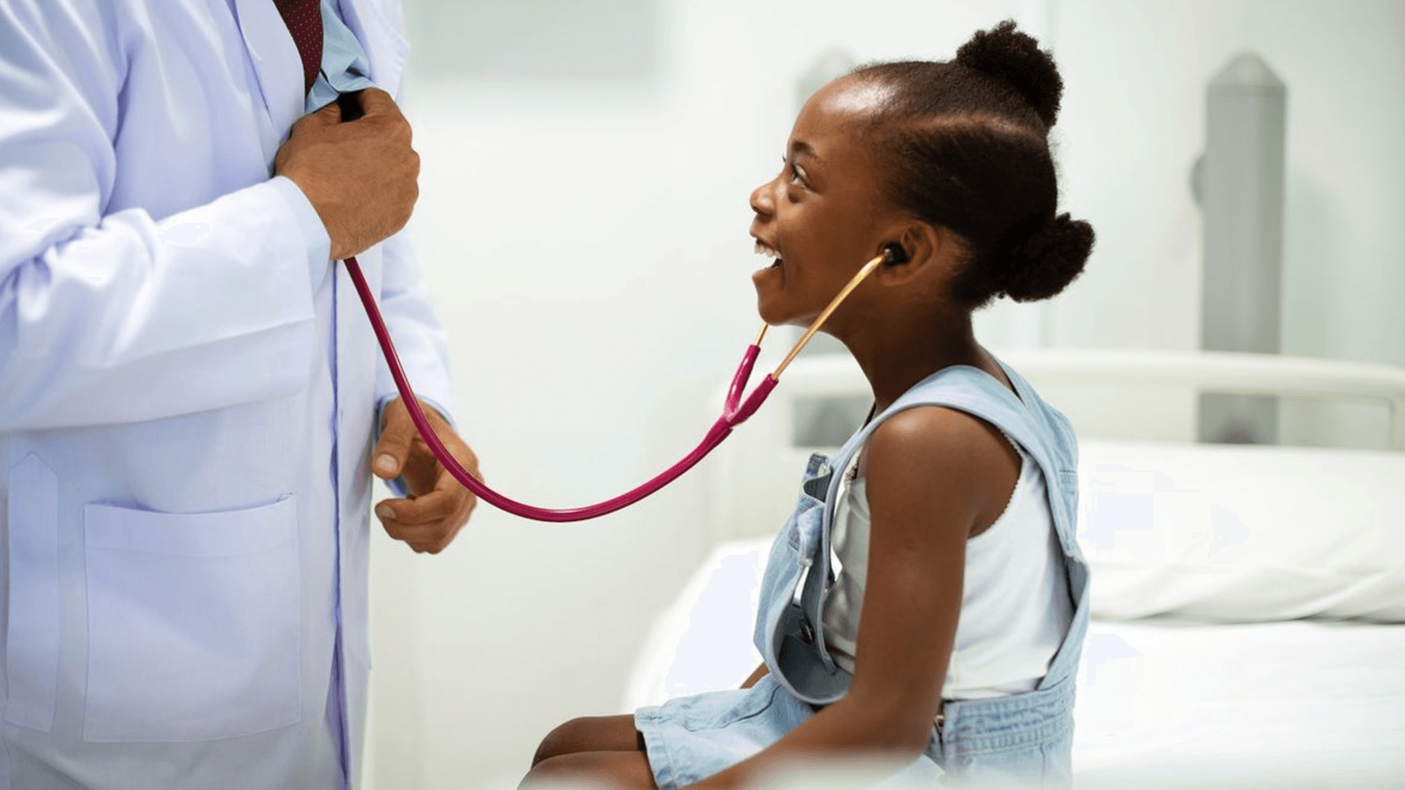 Médico auscultando o coração de uma criança sorridente